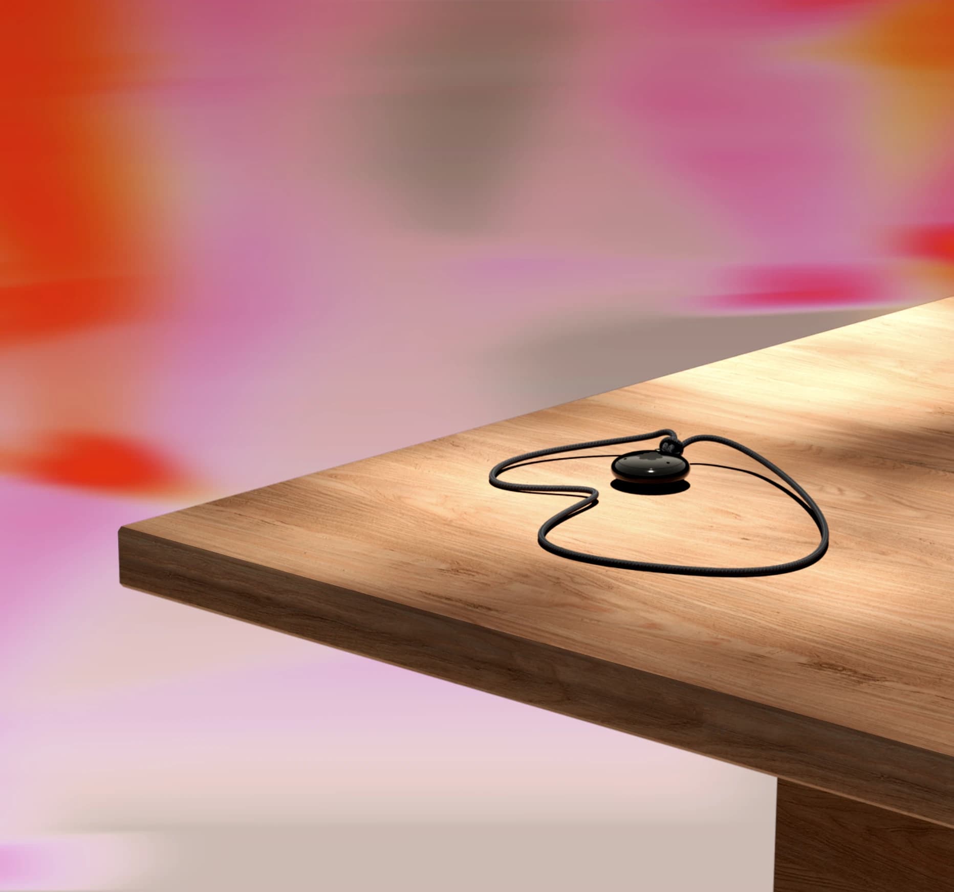 Black Fieldy 3 pendant and cord resting on a wooden table