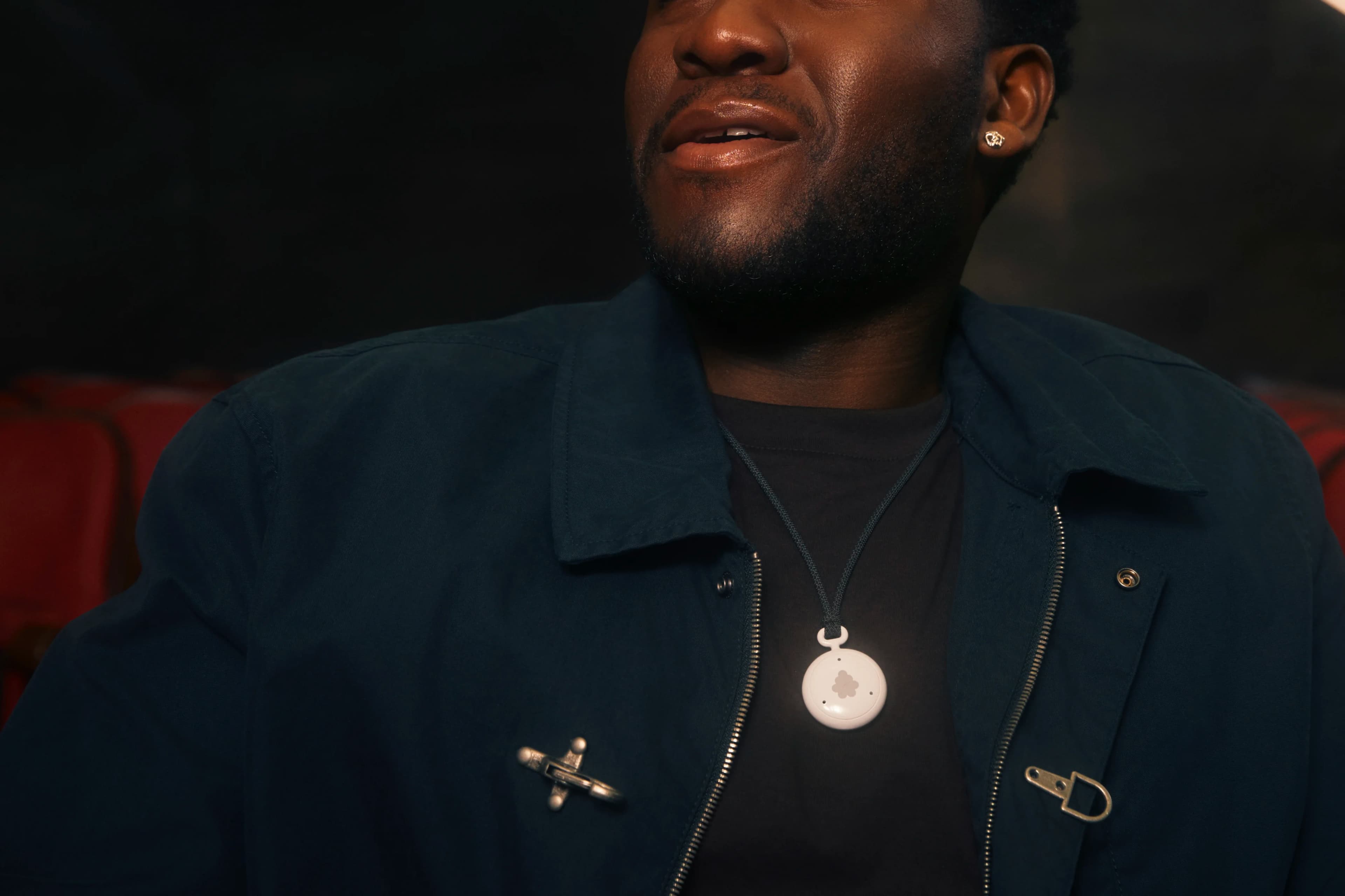 A person wearing the white Fieldy 3 AI pendant on a black cord
